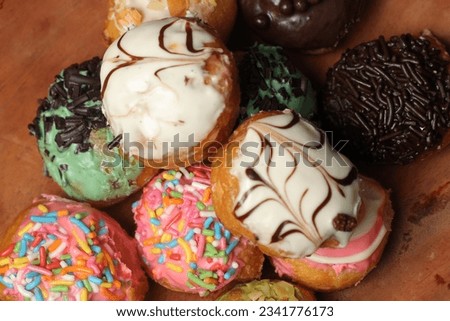 colorful donuts with various flavors on a brown wooden plate.  suitable as a commercial photo
