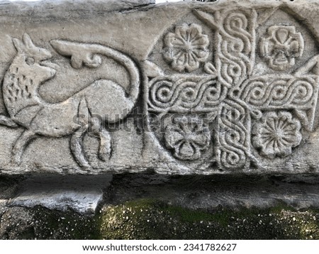 Animal figures and symbols carved in stone. Bas-reliefs on gray ancient stone. Ethnic Carved Ornament. Rough texture grunge background.