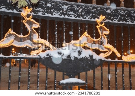 Glowing silhouettes of Christmas deer on the fence. Outdoor festive Christmas decoration, beautiful entrance decoration.