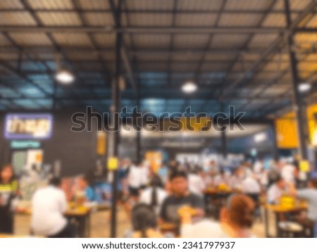 The picture blurs the atmosphere inside a Korean BBQ restaurant with many people eating and coming over.