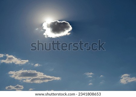Sun hiding behind a cloud on the day sky. Bright Sun Sky. Sun behind the cloud. Nature composition.