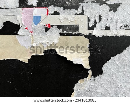 Close up detail of ragged weathered old glue plastered paste up street poster bits Royalty-Free Stock Photo #2341813085