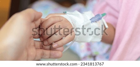Mother holding child hand with saline IV solution in hospital Royalty-Free Stock Photo #2341813767