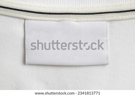 Blank white laundry care clothes label on white shirt fabric texture background