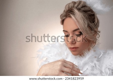 Portrait of a beautiful bride with a wedding hairstyle dressed in a white dress with feathers. A girl with a professional makeup against the wall Royalty-Free Stock Photo #2341823959