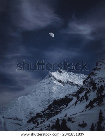 moon shining above snow peaked mountains