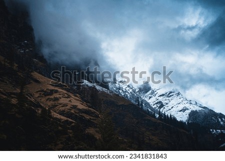 stormy clouds hovering on snow peaked mountains