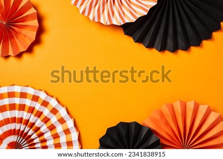 Halloween frame made of paper fans on orange background. Flat lay, top view.