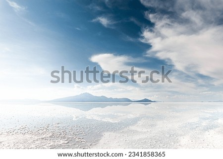 Salt surface with water in Salar de Uyuni salt flat in Bolivia. Sky with clouds are reflected in the water at sunset.  Royalty-Free Stock Photo #2341858365