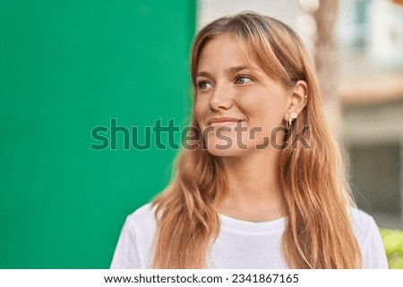 Young blonde girl smiling confident looking to the side at street