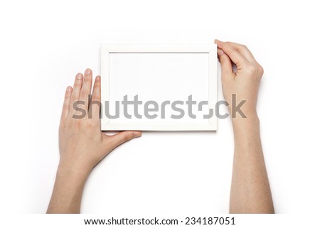 A female hands hold a white wood photo(picture) frames isolated white, top view at the studio.