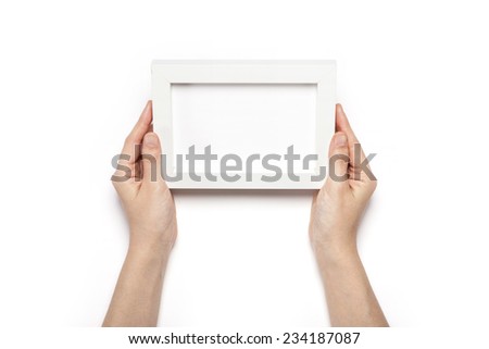 A female hands hold a white wood photo(picture) frames isolated white, top view at the studio.