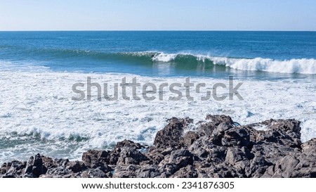Surfing distant surfer riding ocean wave in a rocky beach cove a scenic lifestyle landscape.