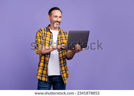 Photo of cheerful pleasant man with white gray beard wear yellow plaid shirt read post on laptop isolated on purple color background
