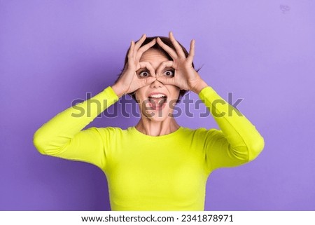 Photo of young girl childish surprised laugh joking open mouth crazy entertainment fingers binoculars isolated on violet color background
