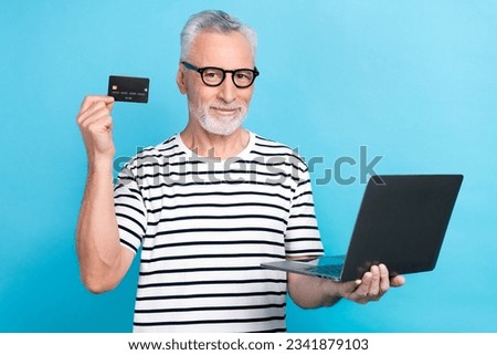 Photo portrait of funny old male hold laptop credit card eshopping wear trendy striped garment isolated on blue color background