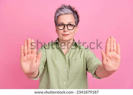 Photo of serious strict old pensioner businesswoman palms against aggression society keep calm isolated on pastel pink color background
