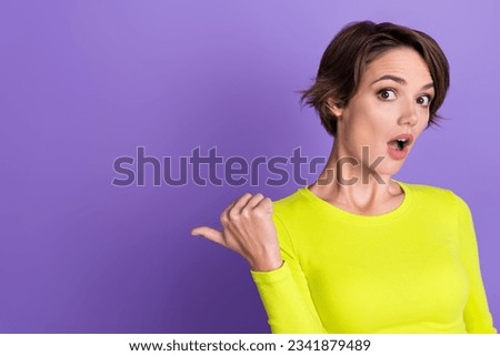 Photo of young advertiser girl bob brown hair wear yellow crop top indicate finger mockup breaking news isolated on violet color background
