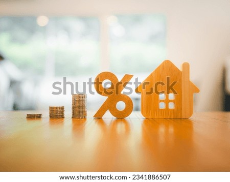 Percentage and house symbol with coins stack on wood table. Concepts of home interest, real estate, investing in inflation.