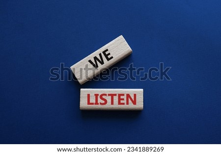 We listen symbol. Wooden blocks with words We listen. Beautiful deep blue background. Business and We listen concept. Copy space. Concept word