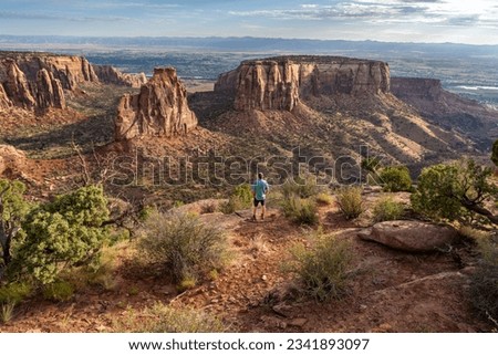 Mature Caucasian man, hiker, standing watching a natural occurring free standing pillar, Independence Monument, Colorado National Monument, Colorado Royalty-Free Stock Photo #2341893097