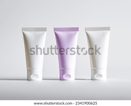Pink cream tube among white cosmetic product packages. Cosmetics choice concept.