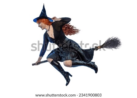 Halloween Witch flying on a broomstick. Female wizard fairy character for All Saints' Day. Fantasy gothic red-haired sorceress girl dressed in black carnival costume. Enchantress woman Royalty-Free Stock Photo #2341900803