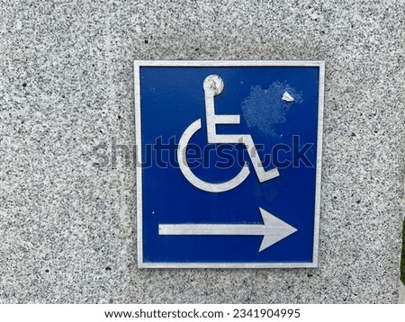 Disabled Accessibility sign on a grey wall. San Francisco, CA, USA.