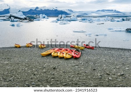 the joekulsar lagoon with icebergs  and eroding glacier in Iceland and empty canoes at the beach for rent