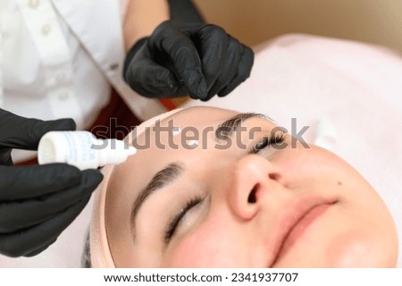 A cosmetologist applies couperosis cream to a girl's face, a procedure to reduce couperosis on the face. Royalty-Free Stock Photo #2341937707