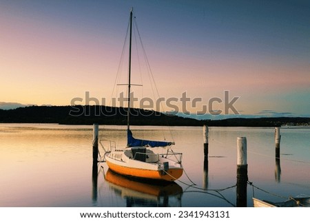 Little sailing boat or yacht tied to its moorings. Sunrise at Woy Woy, N-SW, Australia. Woy Woy is aboriginal l ---Wy Wy---, which means -much water- or -big lagoon-