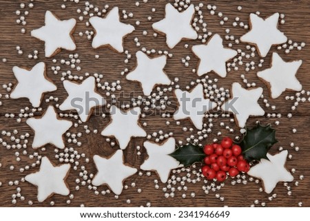 Christmas star gingerbread biscuits with holly and silver balls over old oak wood background