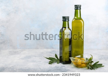 Olive oil in a bottle and gravy boat on the kitchen table. Oil bottle with branches and fruits of olives. Place for text. copy space. vegetable oil and salad dressing.