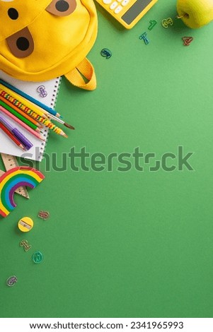 Organized school setup: vertical top view flat lay arrangement of color pencils, markers, drawing supplies, calculator, clips, bag, apple on green chalkboard with vacant space for text or advert