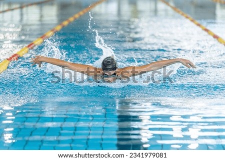 Front view of a powerful elite female swimmer competitor performing butterfly swim technique, arm stroke movements. Swim fly and dolphin kick concept.