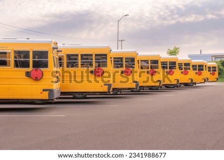 Yellow electric school bus plugged in at a charging station. Royalty-Free Stock Photo #2341988677