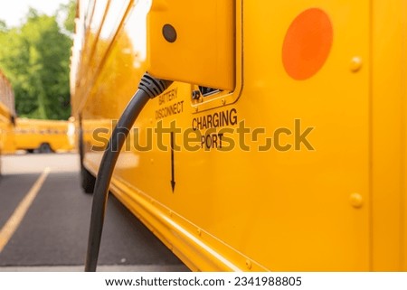Yellow electric school bus plugged in at a charging station. Royalty-Free Stock Photo #2341988805