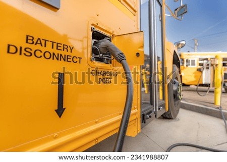 Yellow electric school bus plugged in at a charging station. Royalty-Free Stock Photo #2341988807