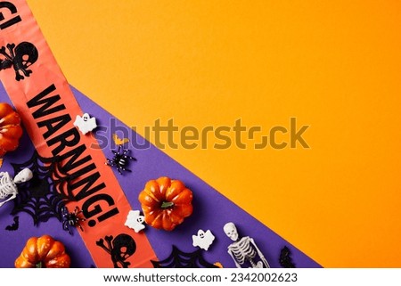 Halloween composition. Flat lay warning tape, pumpkins, Halloween decorations on split orange and violet background.