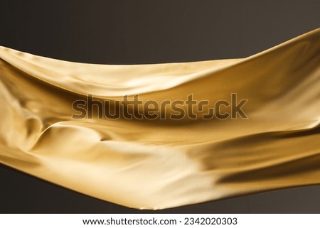 Close up of gold shiny silk fabric with copy space on black background. Texture, fabric, cloth, colour and material.