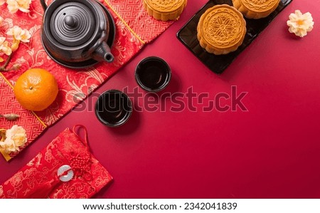 Chinese Mid-Autumn Festival concept made from mooncakes, tea and plum blossom on red background.