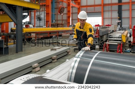 Industrial diligent worker safeguarded by a hard hat, engrossed in his duties amidst the complex machinery of a bustling factory. Royalty-Free Stock Photo #2342042243