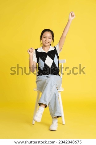 fullbody image of asian girl sitting and posing  on yellow backg Royalty-Free Stock Photo #2342048675