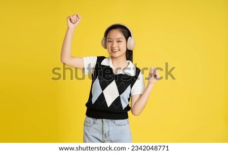 Portrait of a beautiful asian girl posing on a yellow background
