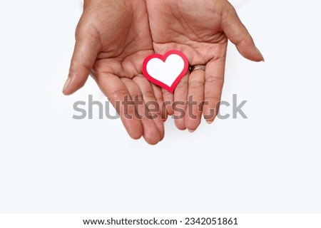 Hand holding a red and white paper heart love-shaped with empty copy space isolated on a white background, representing Indonesia Independence Day concept