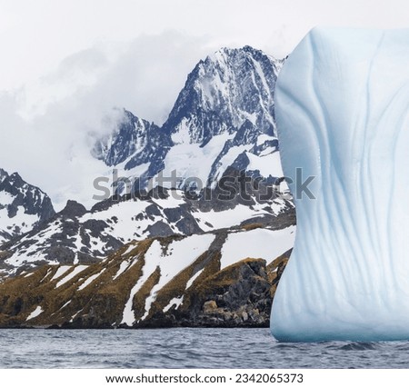 Fluted berg and mountains, of Cooper Bay; South Georgia; Iceberg against dark sky, Cooper Bay, South Georgia