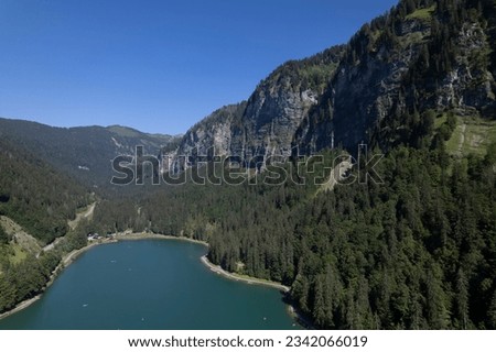 Montriond lake seen from above. Aerial of French Alps mountain range and leisure melt water pond during summer.