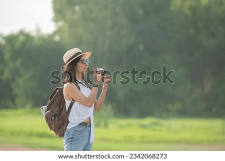 Hipster woman with backpack taking photo of amazing landscape sunset on vintage camera on peak mountain. Joyful asian woman travel vacation. Tourist traveler on background sunlight in trip in nature