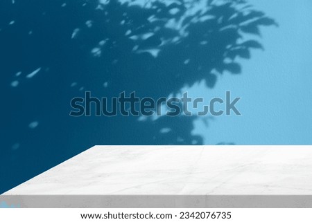 Minimal White Marble Table Corner with Light Beam, Shadow, and Spotlight on Blue Concrete Wall Background, Suitable for Product Presentation Backdrop, Display, and Mock up. Royalty-Free Stock Photo #2342076735