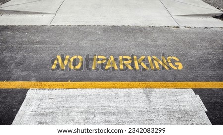 No Parking Sign on the road. Yellow no parking lines on fresh road. No parking signage on a concrete floor. No parking text written and white line with broken cement wall, sign word on street. 